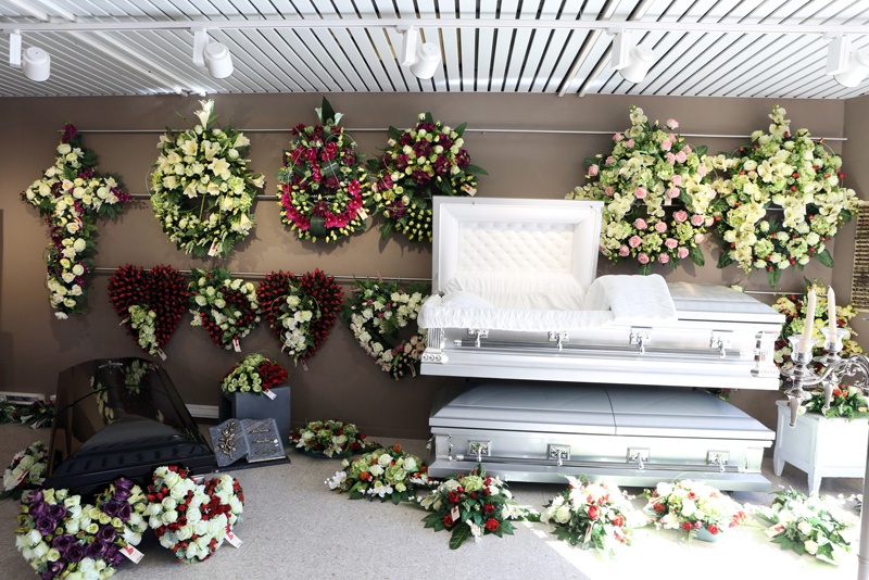 Produits vendus par la maison funéraire Fossoises avec une présentation de cercueils, d'urnes, d'ornement de tombe et de composition florales.